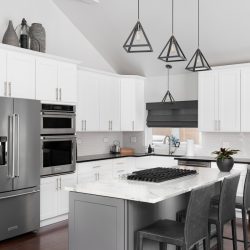 beautiful white kitchen in a modern farmhouse with black lights hanging from the vaulted ceiling over the island bar stools and KitchenAid steel appliances, KitchenAid Refrigerator Not Cooling - What To Do?