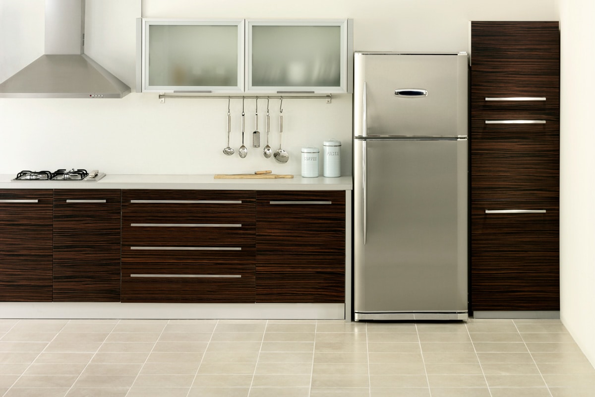 Classic interior of a modern kitchen with wooden cabinets and white countertop and a refrigerator on the side