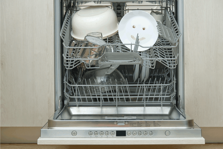 Fine washed dishes in the dishwasher. Integrated Dishwasher with white plates front view. KitchenAid Dishwasher Door Not Closing - What To Do