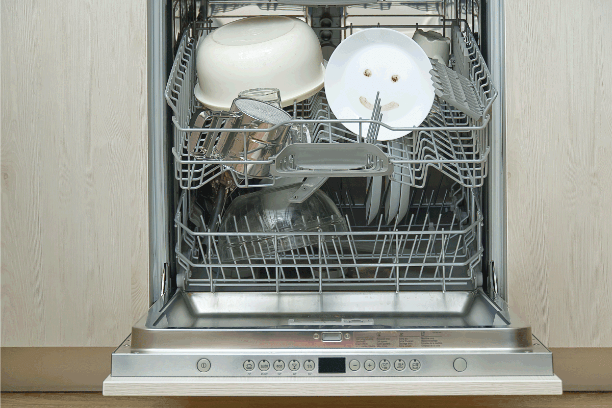 Fine washed dishes in the dishwasher. Integrated Dishwasher with white plates front view. KitchenAid Dishwasher Door Not Closing - What To Do