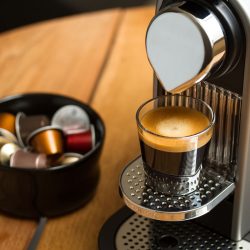 Freshly brewed espresso in glass standing on silver Nespresso coffe machine, Nespresso Machine Leaking - What To Do?