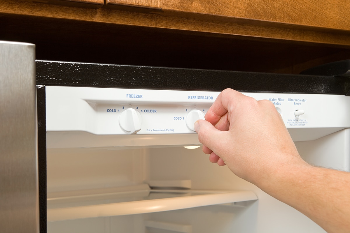 Hand adjusting new refrigerator thermostat control knob