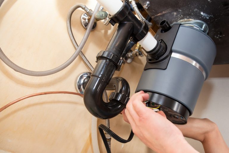Man installing garbage disposal in home - Where Is The Best Location For Garbage Disposal Switch