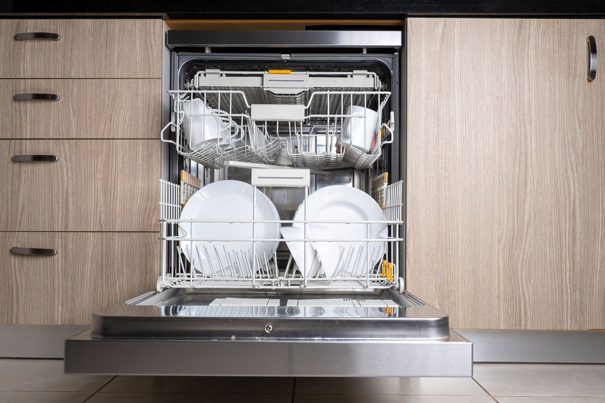 Open door of built-in dishwasher, Kitchen with integrated appliances, Plates and dishes in the dishwasher