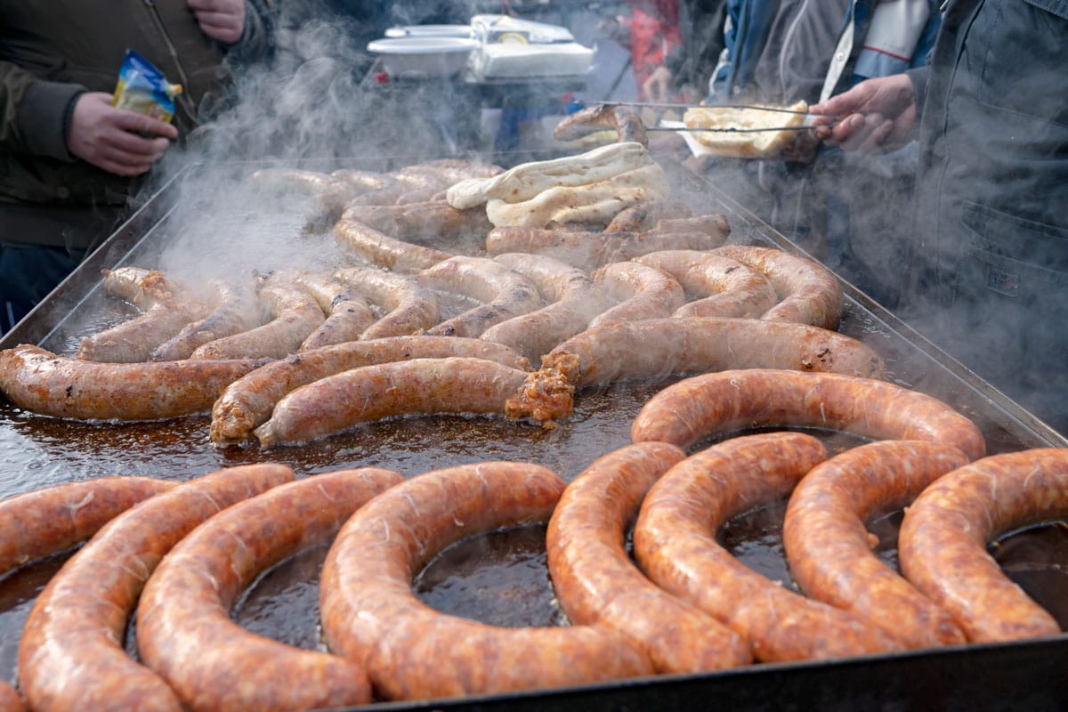 Street Food Market Vendor Cooking and Selling Sausage in griddle