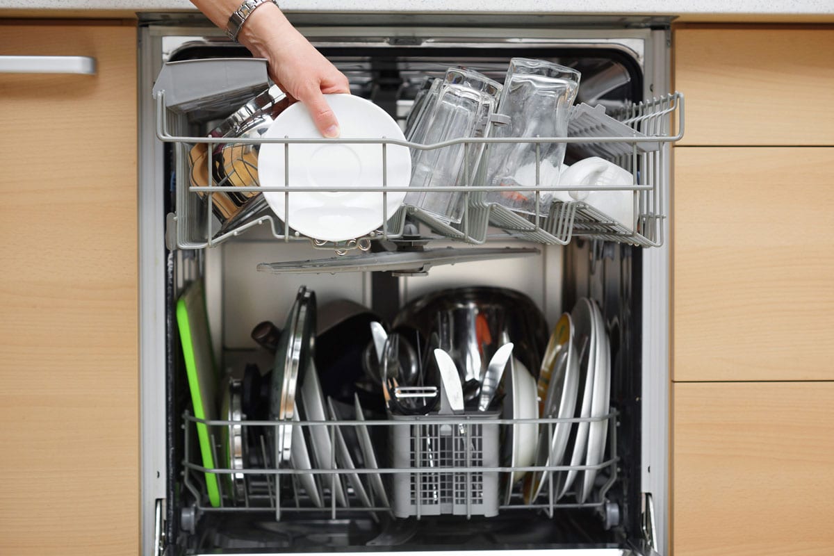 Woman is using a dishwasher in a modern kitchen