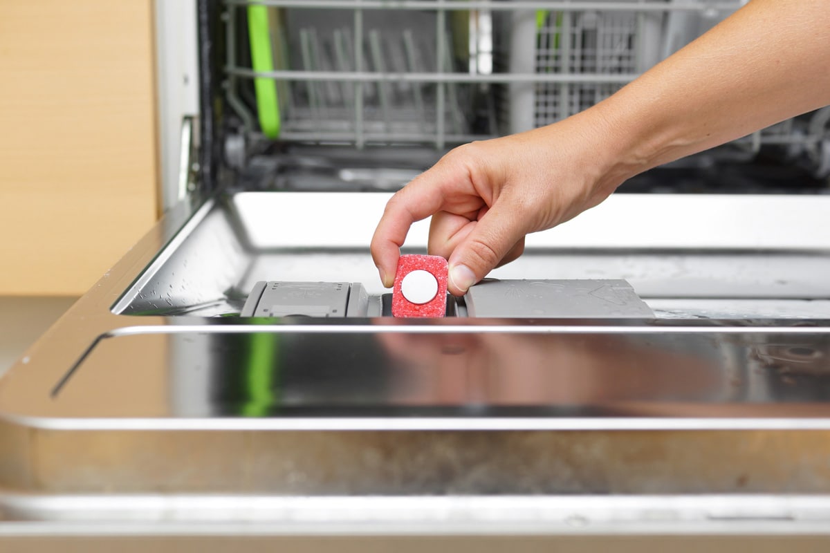 Woman putting a small detergent tablet to the dishwasher