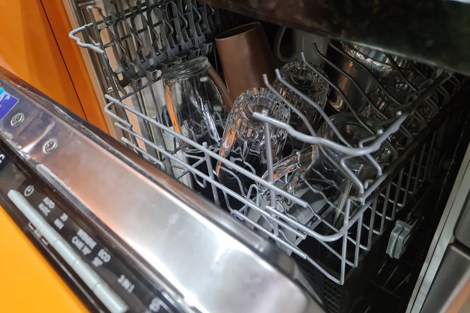 loseup of open dishwasher with clean glasses and dishes. Washing dishes and household appliances concept