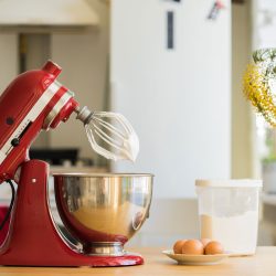 red stand mixer mixing cream with 4 eggs and a plastic ware on a table, Kitchenaid Mixer Head Wobbles And Bounces - What's Wrong?