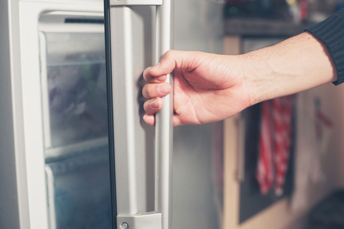 up close photo of a man hand holding the refrigerator handle opening the door