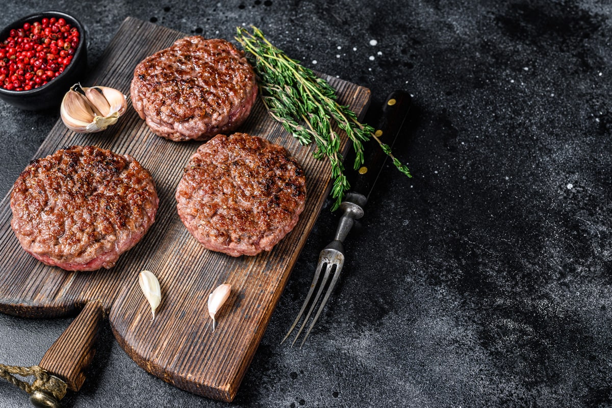 BBQ grilled beef meat patties for burger from mince meat and herbs on a wooden board. 