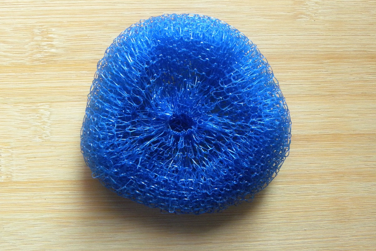 Blue color plastic dish scrubber kept on wooden table