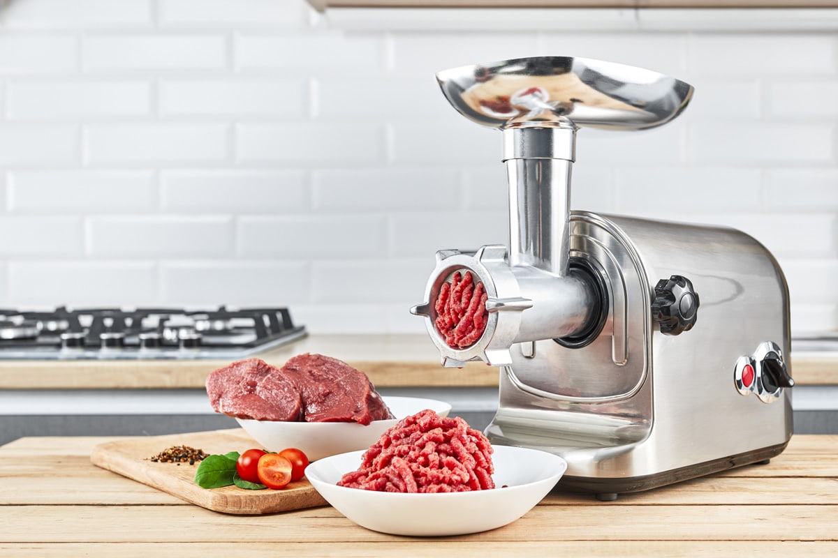 Bowl of mince with electric meat grinder in a kitchen interior