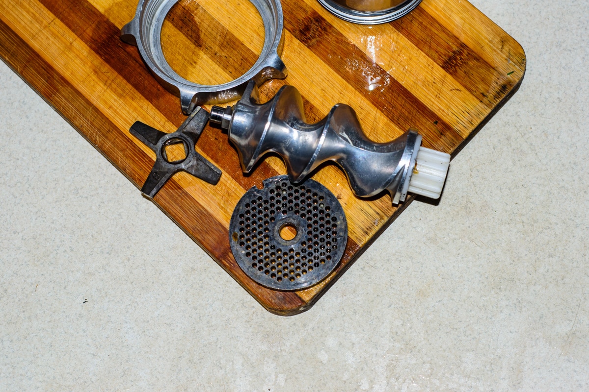 Disassembled electric meat grinder on cutting board