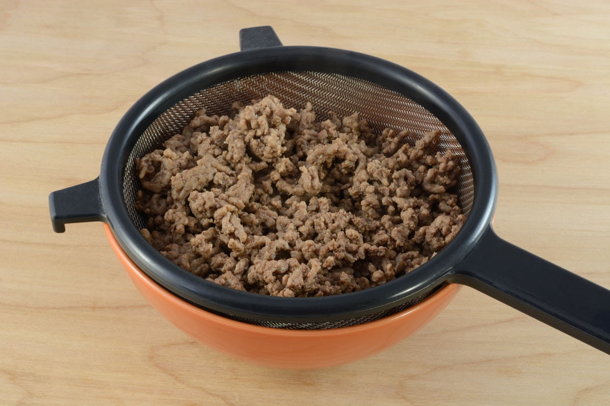Draining fat and grease from cooked hamburger meat in strainer in bowl for spaghetti sauce