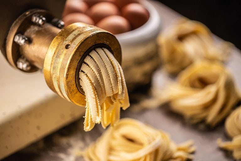 Fresh fettuccine pasta getting out of the pasta making machine, Can You Use A Meat Grinder To Make Pasta And Other Noodles?