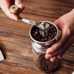 Grinding coffee beans in a manual coffee grinder on a wooden table. Can You Grind Salt In A Coffee Grinder Or Food Processor?