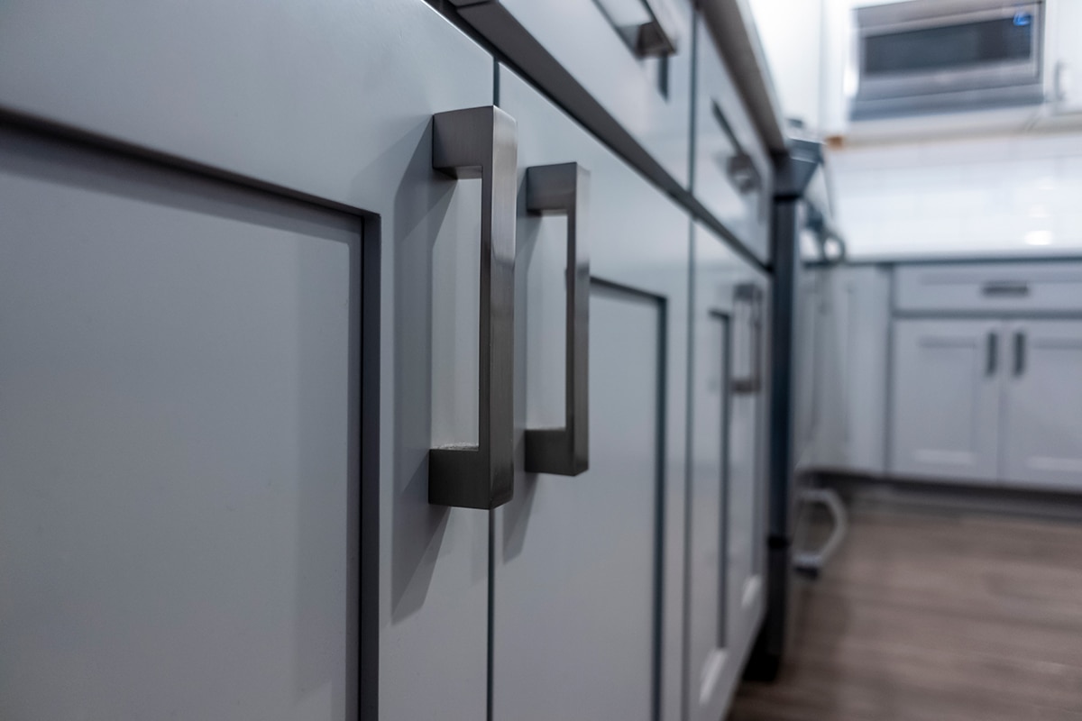 Low angle view of gray kitchen cabinet door handles inside a large beautiful kitchen