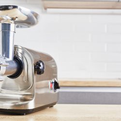 A meat grinder on a wooden table in kitchen, Can You Use A Meat Grinder To Rice Potatoes?
