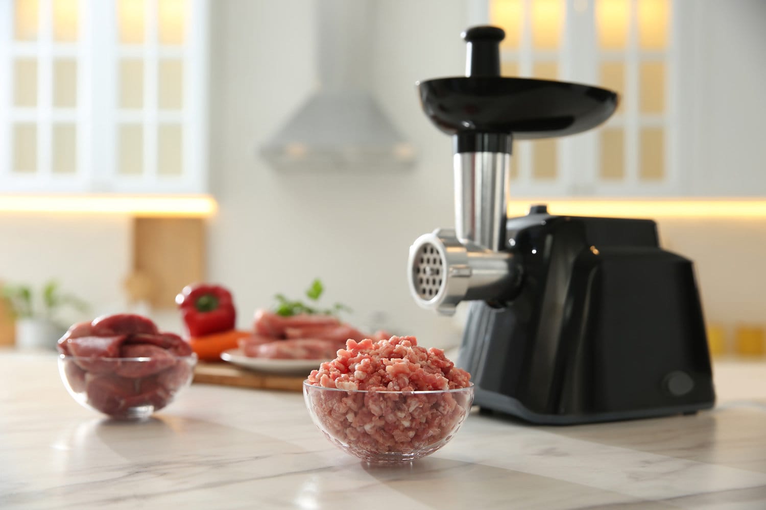 Modern grinder in kitchen, focus on bowl of minced meat. Space for text