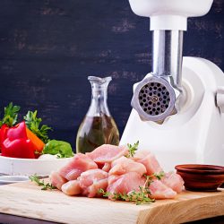 Raw chopped chicken breast fillets on wooden cutting board and meat grinder, Best Meat Grinder For Chicken Bones - How To Choose?