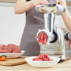 Grinding fresh red meat on a metal manual meat grinder, close-up on a brick wall background with copy space. - Can I Grind Meat With Silver Skin?