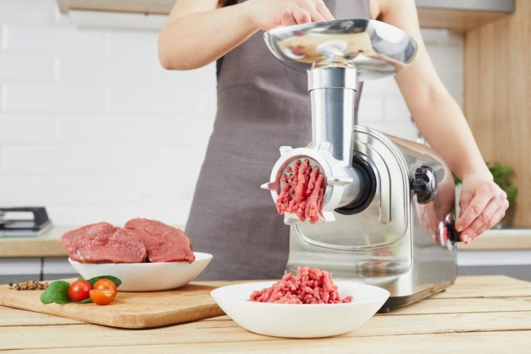 Grinding fresh red meat on a metal manual meat grinder, close-up on a brick wall background with copy space. - Can I Grind Meat With Silver Skin?