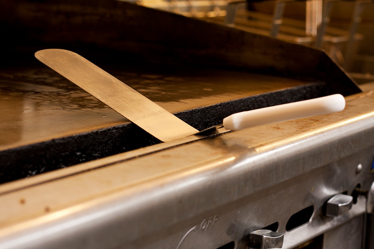 Restaurant grill spatula on the greese trough of a grill in a restaurant kitchen
