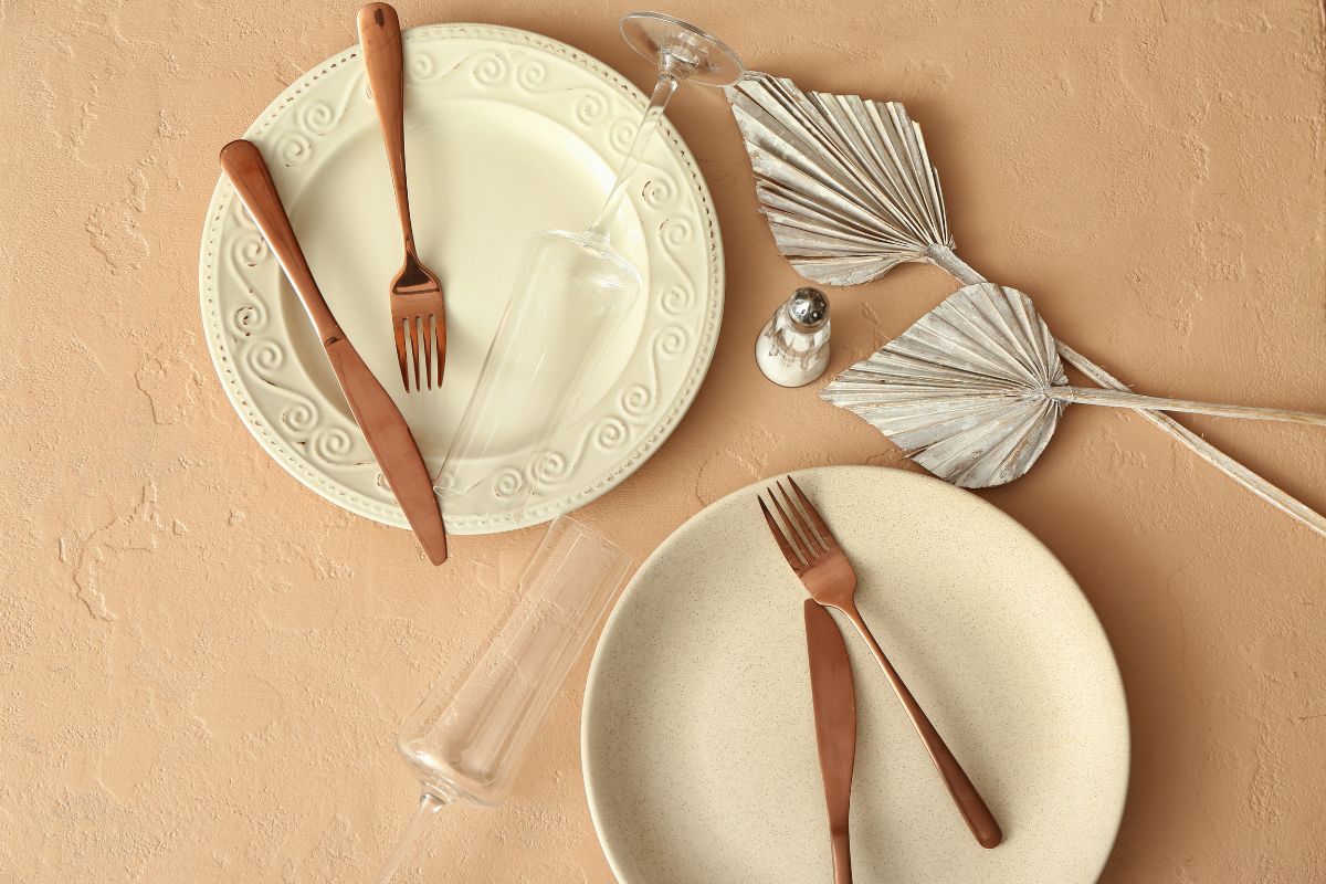 Simple table setting and decorative palm leaves on beige background