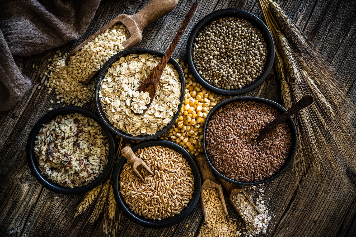 Top view of wholegrain and cereal composition shot on rustic wooden table. This type of food is rich of fiber and is ideal for dieting. The composition includes oat flakes, brown rice, dried corn,spelt, hemp seeds and flax seeds. Predominant color is brown.
