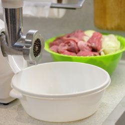 Meat grinder for fresh meat on a wooden table in kitchen interior. - What Kind Of Oil Should You Use In A Meat Grinder