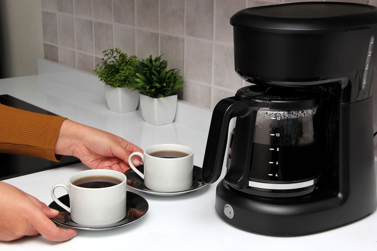 Woman's hands serve coffee prepared in a coffee maker to start the day