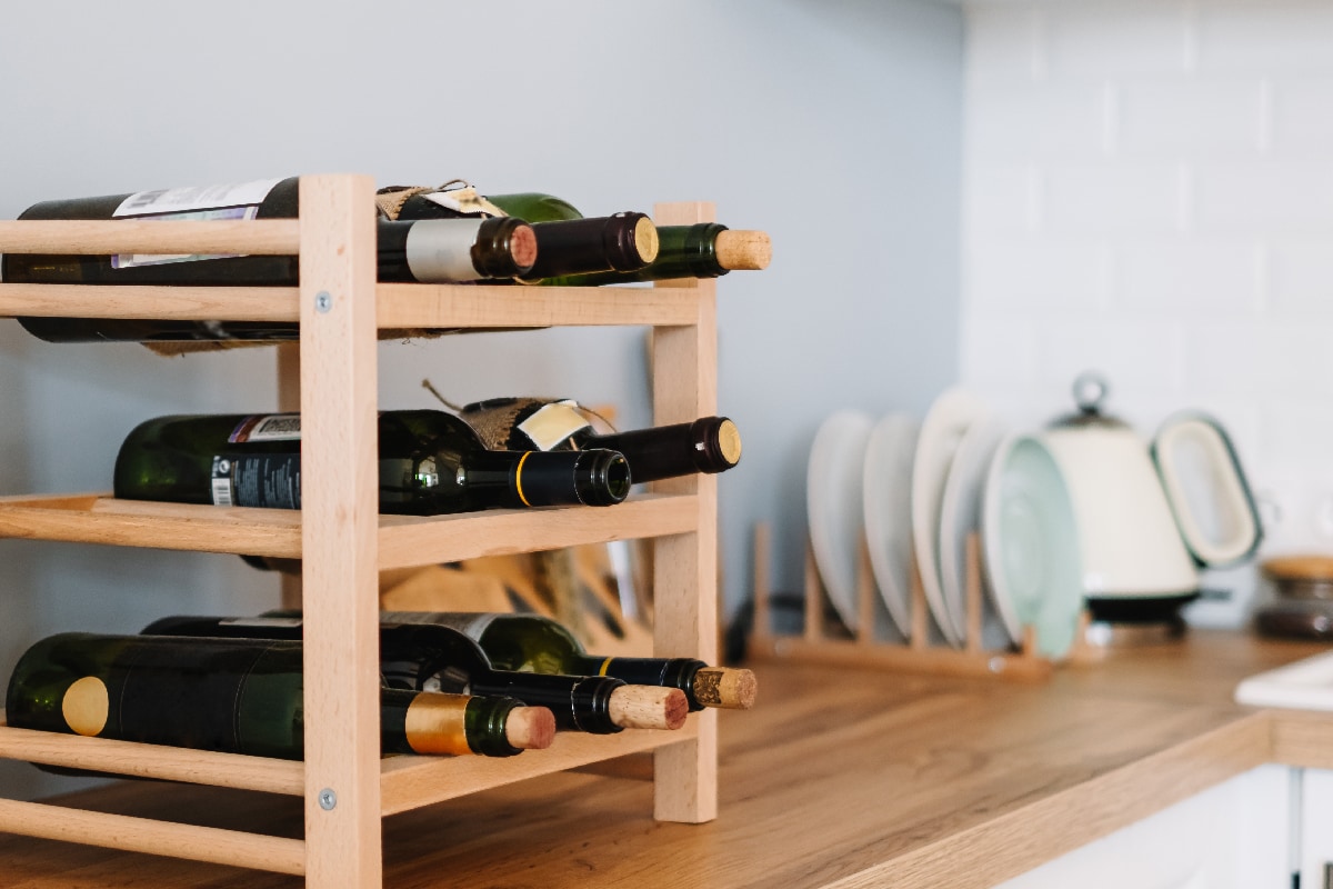 Wooden wine shelves with bottles on the table in modern kitchen