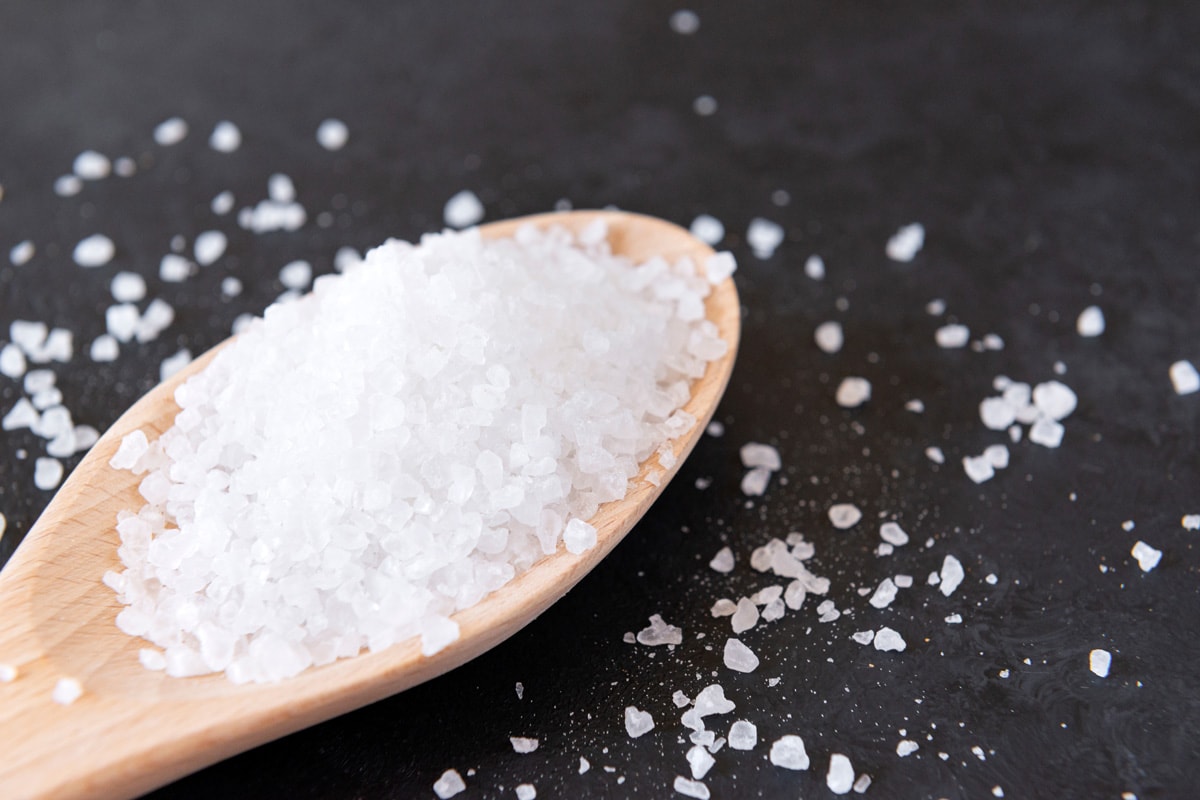 coarse salt closeup, salt in a spoon and scattered on the black powdered,