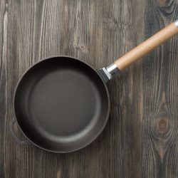empty-cast-iron-frying-pan-on-woodedn-table, X Non Toxic Cookware Options That Are Made In USA - Comprehensive Guide