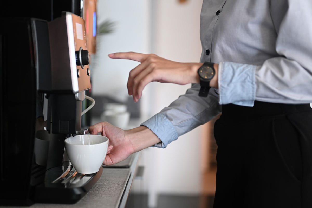 young woman making coffee with coffee machine during office break time