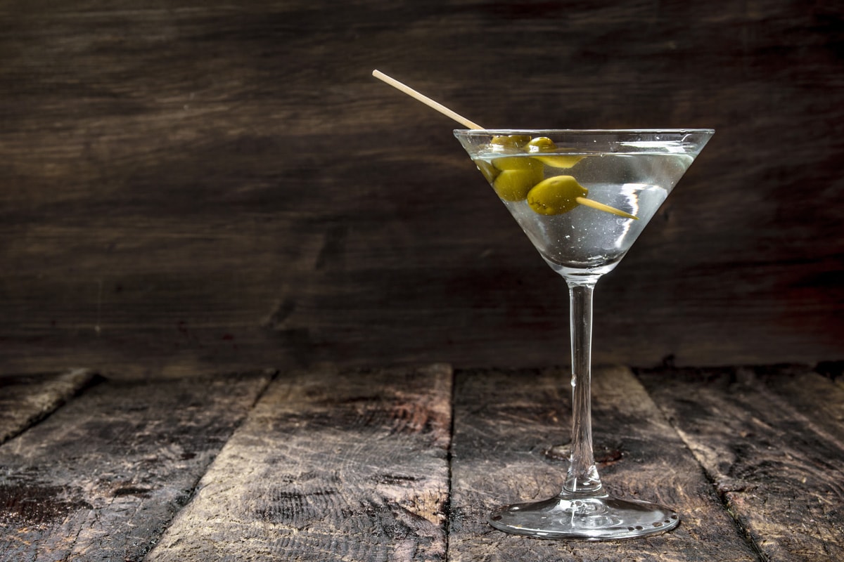 A Martini glass with olives at a bar