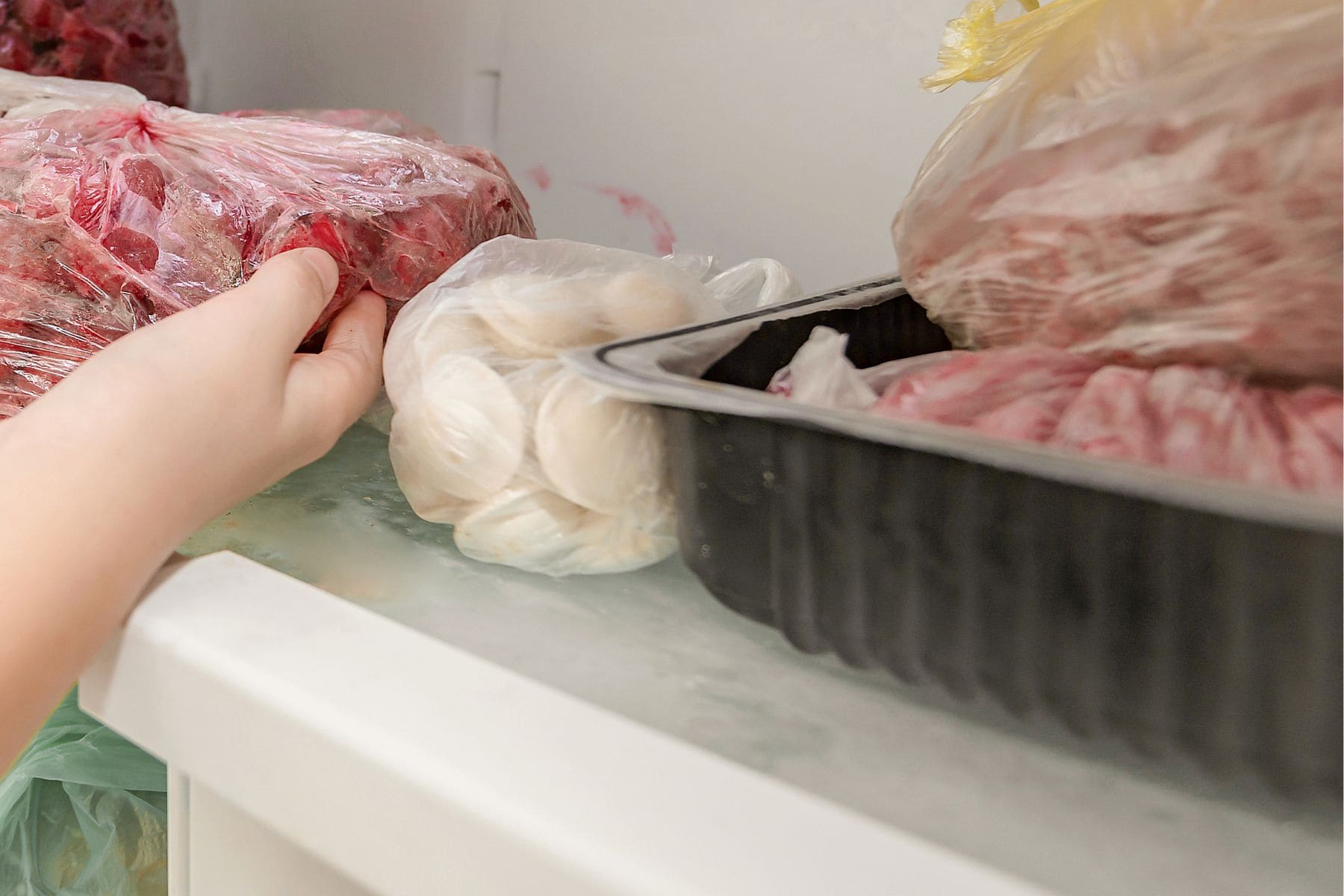 A woman puts frozen fruit products in the freezer, for long-term preservation.