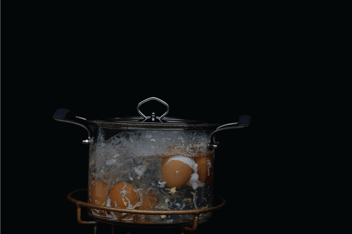Boiling eggs on glass pot over gas stove, Broken eggs in transparent pot