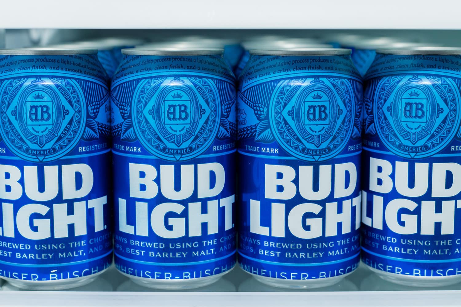  Cans of Bud Light Beer lined up on a shelf in a refrigerator.