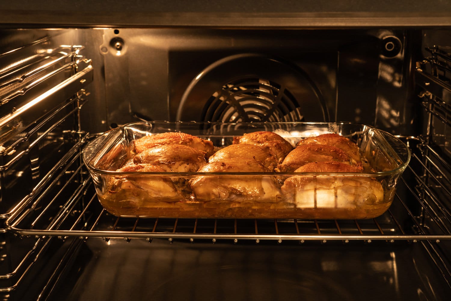 Chicken thighs baked in the oven in glass pan. Homemade food.