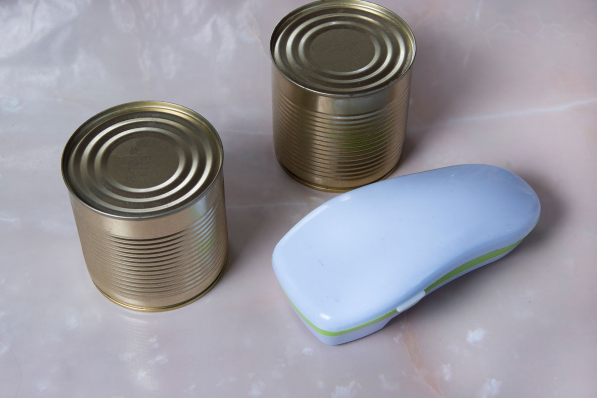 Electric can opener and canned goods on marble kitchen table