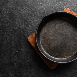 Empty cast iron frying pan for cooking on black background, top view, copy space. Cooking concept background with black pan, How To Tell If Cast Iron Is Seasoned