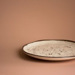 Empty ceramic plate with brown stains isolated on dusty pink, What Stoneware Dinnerware Is Made In The USA? [11 Options To Choose From]