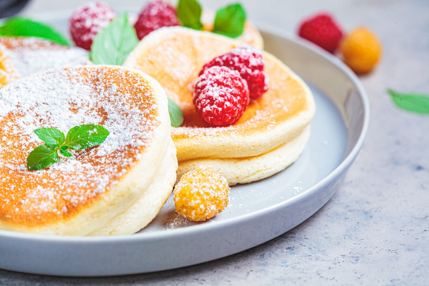 Japanese fluffy pancakes with raspberries in gray plate, gray background. Japanese cuisine