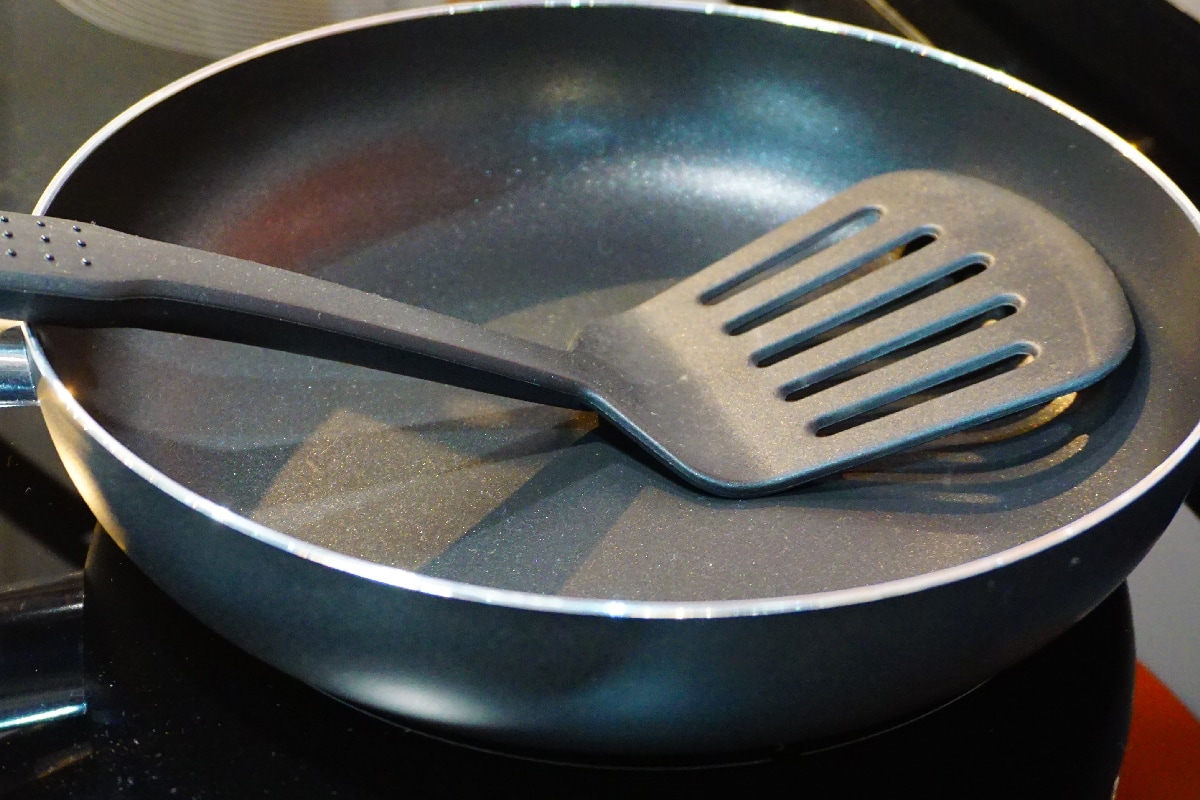 Metal black frying pan with a non-stick coating on electric stove