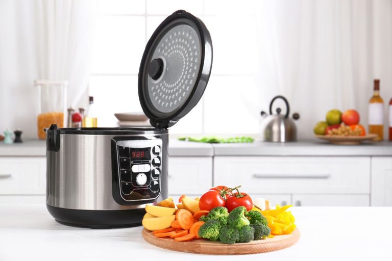 Modern multi cooker and wooden board with vegetables on white table in kitchen. - How To Set All-Clad Slow Cooker [Inc. Timer]