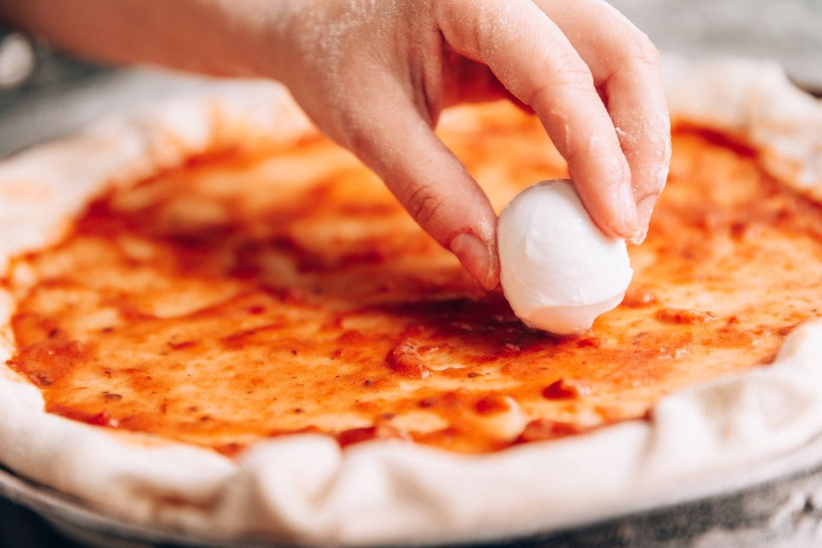Placing mozzarella cheese on pizza pan