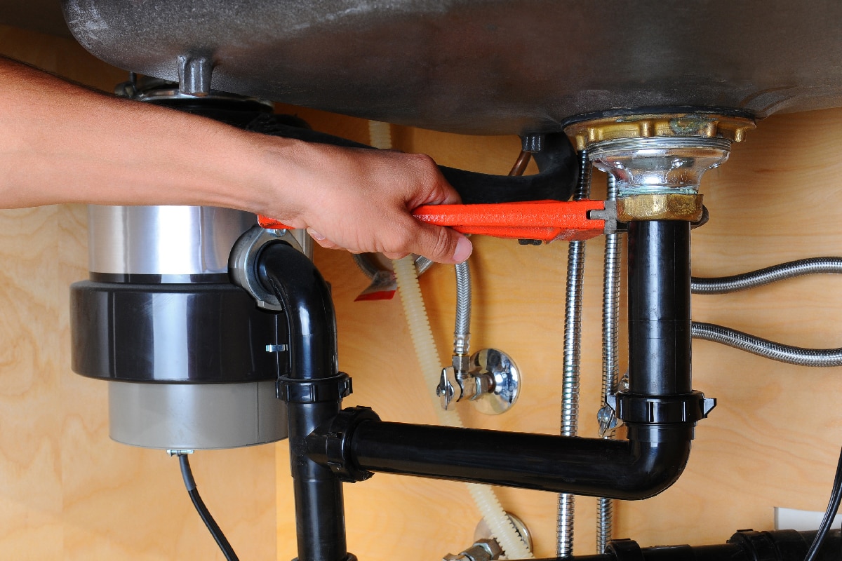 Plumber using wrench under kitchen sink