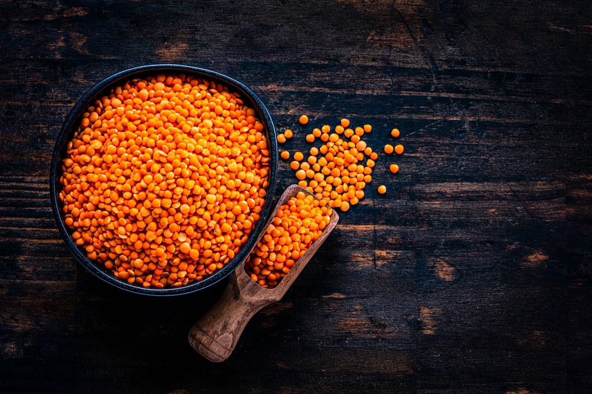 Red light orange lentils in a black bowl in a table
